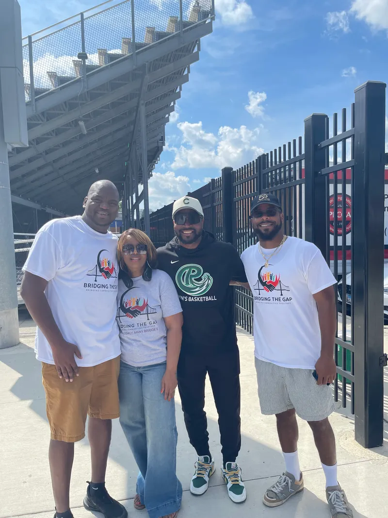 Four people in Bridging the Gap shirts outside a stadium