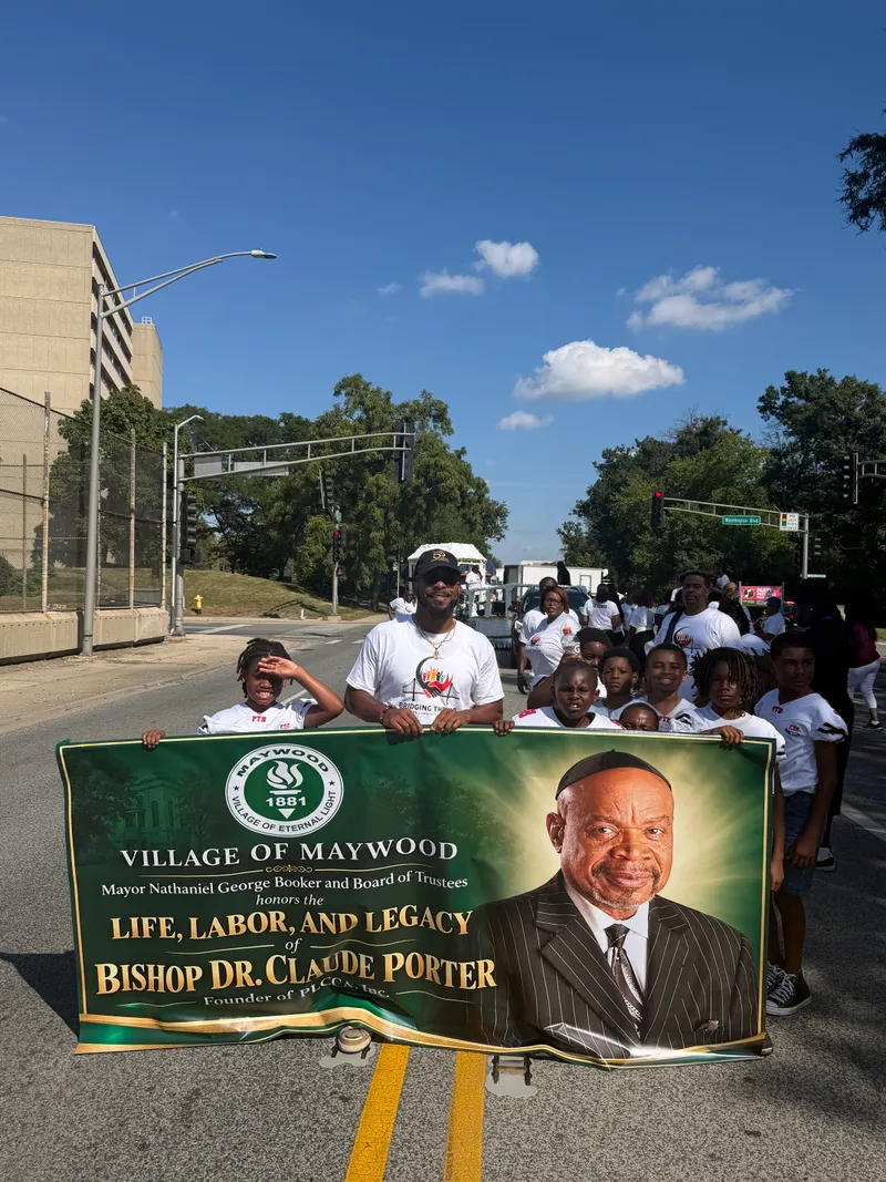 Parade marchers carrying a Village of Maywood banner honoring Bishop Dr. Claude Porter